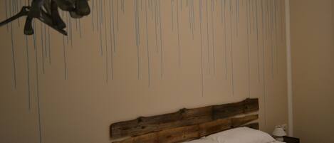 A bedroom with a wooden headboard, a white bed, and a wall with vertical lines.