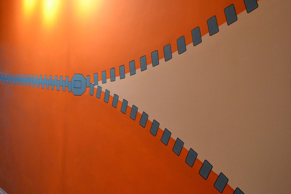 Un couloir aux murs orange et au sol carrelé.