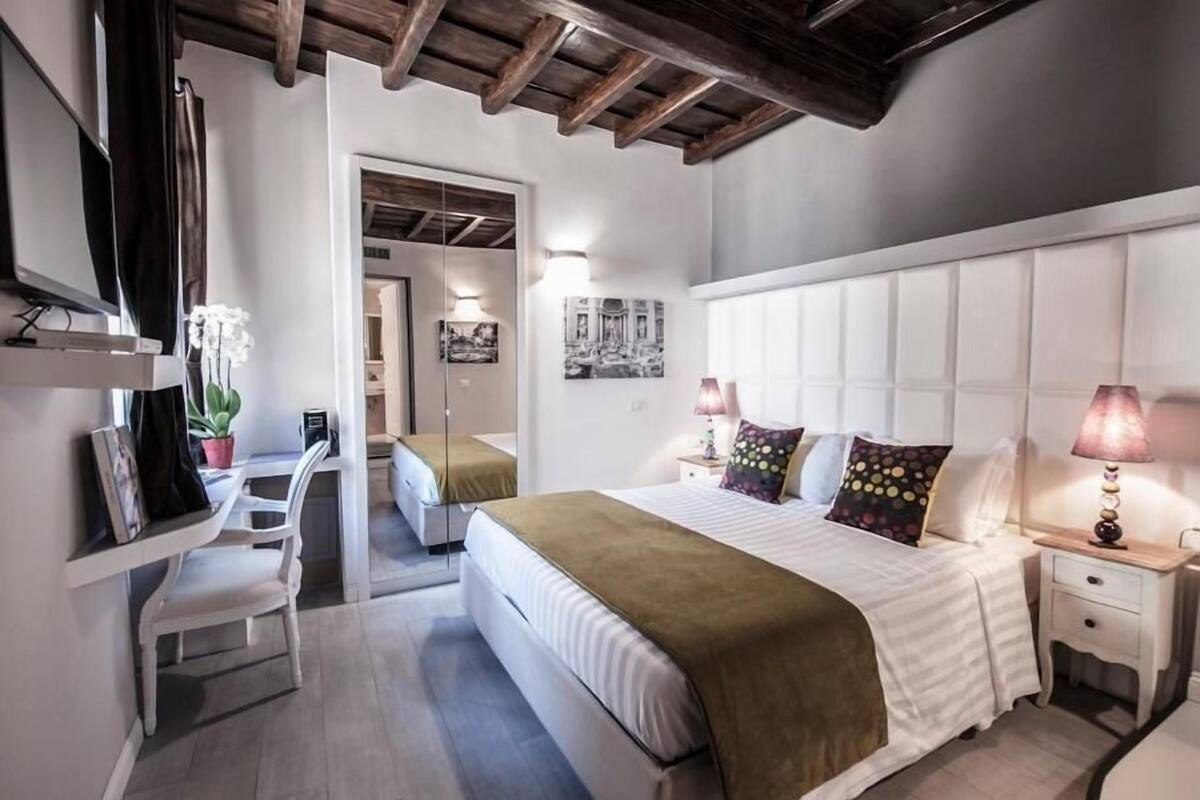 A bedroom with a large bed, bedside tables, a desk, and chairs.