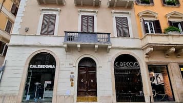 A building with two ground-floor storefronts, one labeled "Calzedonia" and the other "C. Deccio".
