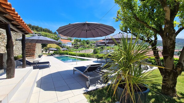 Een buitenzwembad, parasols bij het zwembad en ligstoelen
