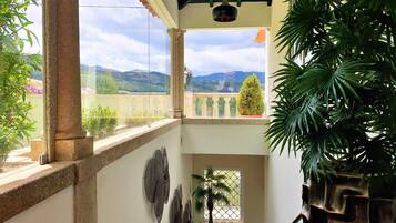 A balcony with a view of mountains, a potted plant, and decorative wall art.