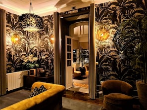 A room with a large open doorway leading to another space, a yellow sofa, and a chandelier. - Quinta da Palmeira - Country House Retreat & Spa (Arganil)