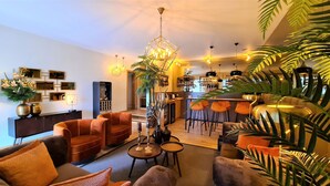 A modern living room with a sofa set, a dining area, and a kitchen in the background.