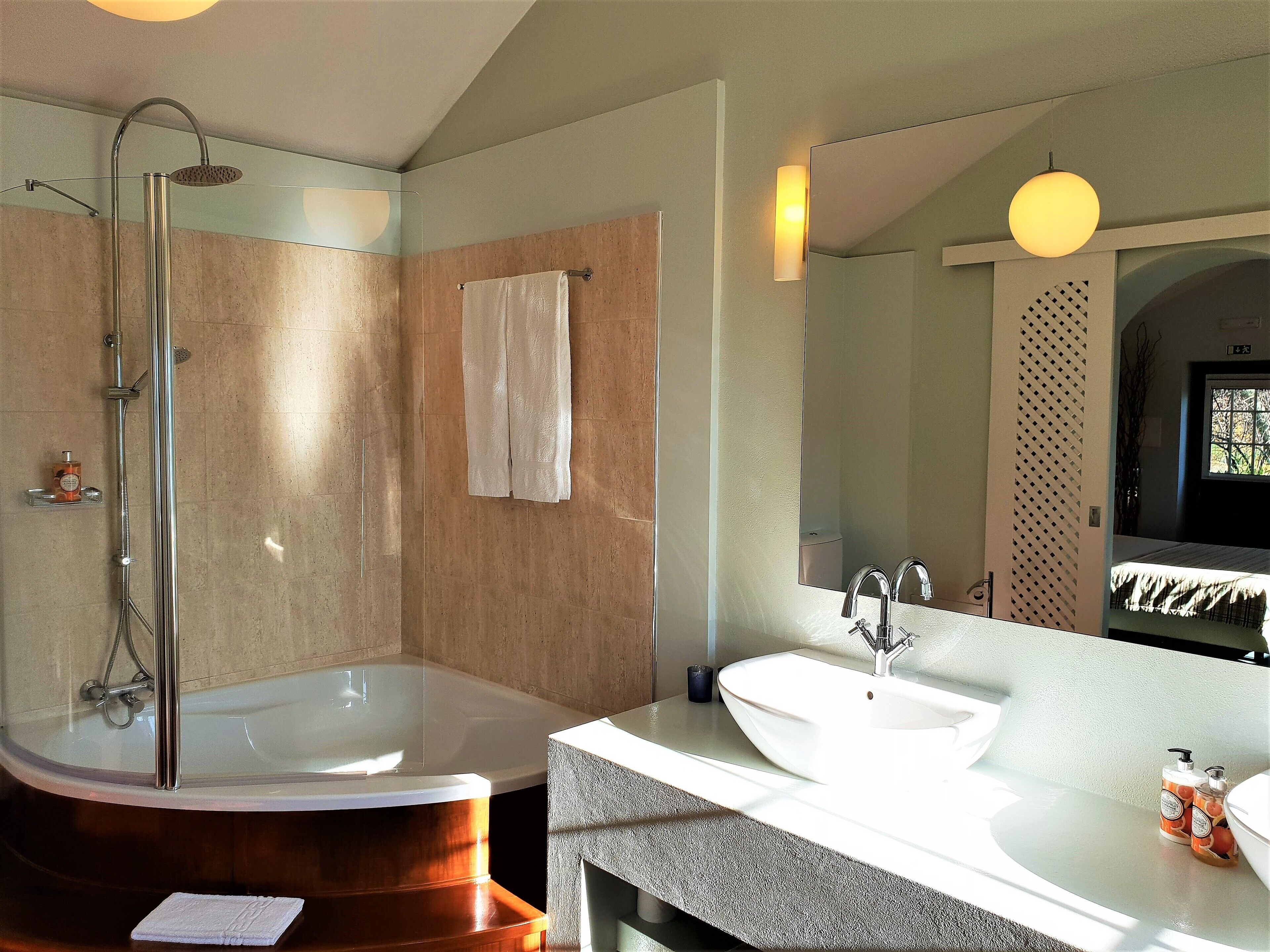 Ein modernes Badezimmer mit einer freistehenden Badewanne, einem großen Spiegel und einem Waschtisch.