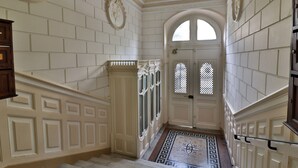 Un amplio pasillo con paredes blancas, piso de mármol y un gran arco.