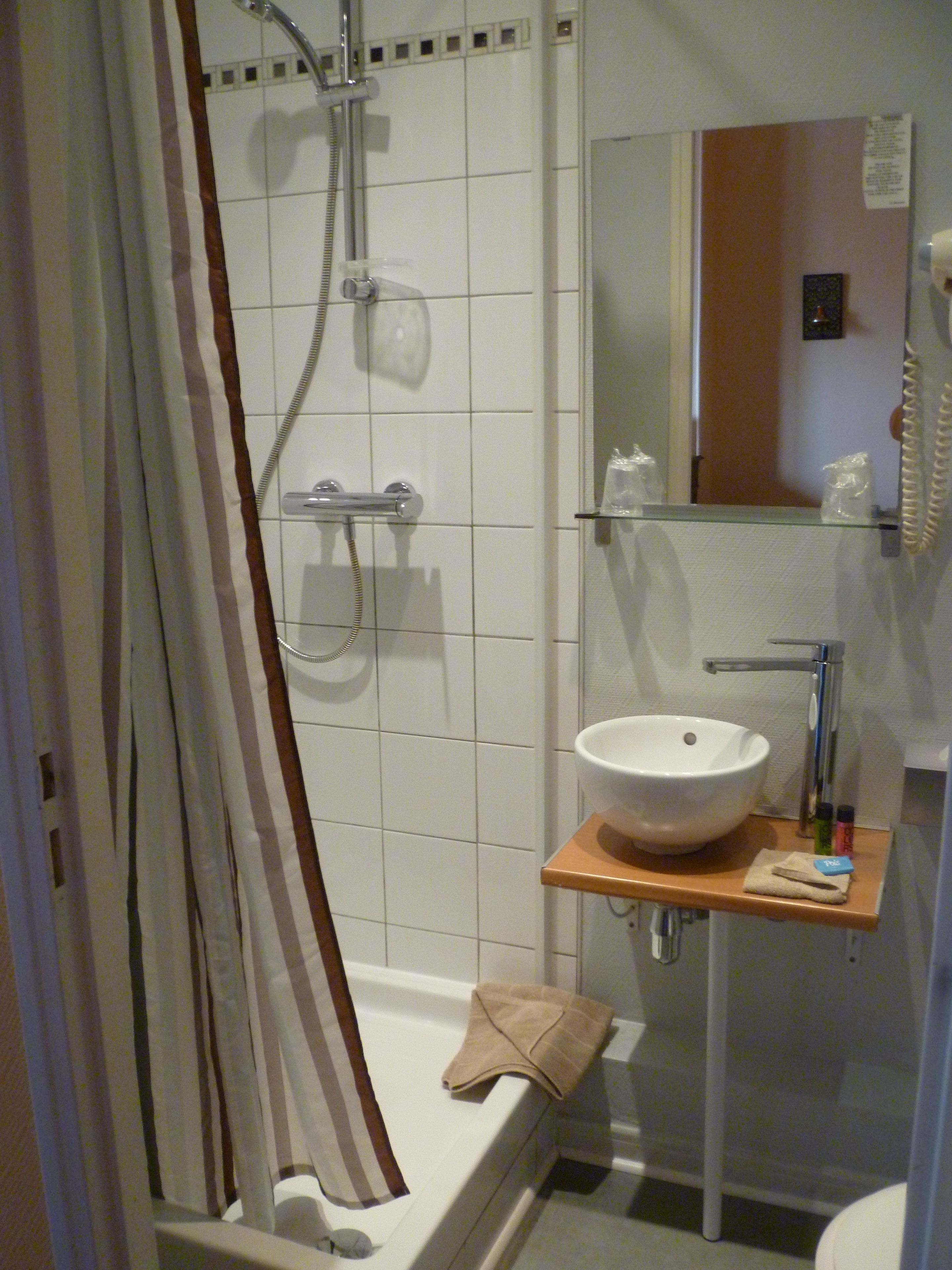 A bathroom with a shower, a sink, and a mirror.
