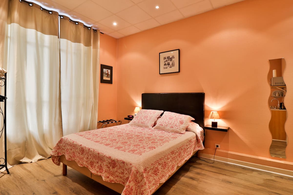 Une chambre à coucher comprenant un lit, des tables de chevet, une commode, un miroir et un tableau accroché au mur.