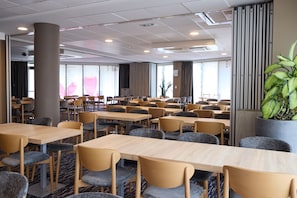 A hotel room with multiple tables and chairs, a large pillar, and a potted plant. - Park Hôtel (Cholet)