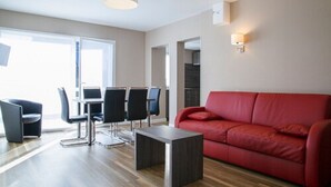Una sala de estar moderna con un sofá rojo, una mesa de comedor con sillas y una mesa de centro.