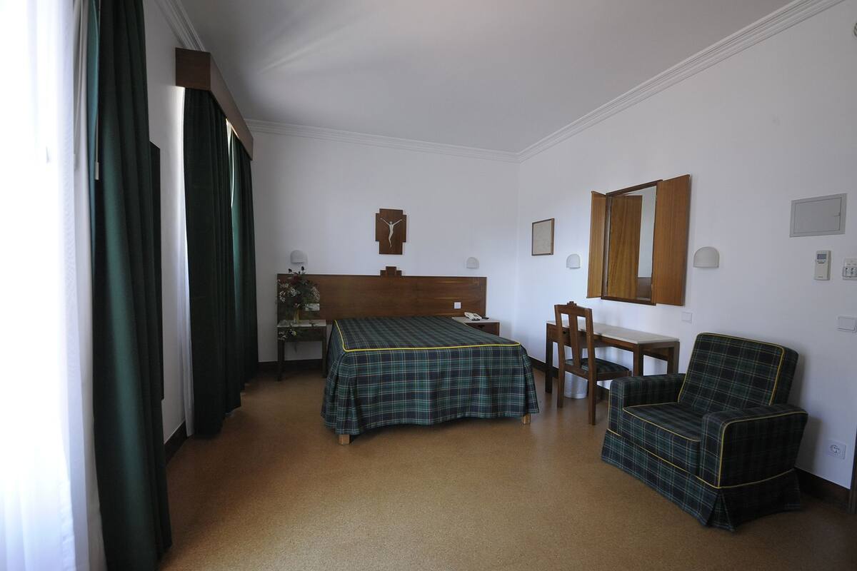 Une chambre d’hôtel avec un lit, un bureau, une chaise et un miroir.