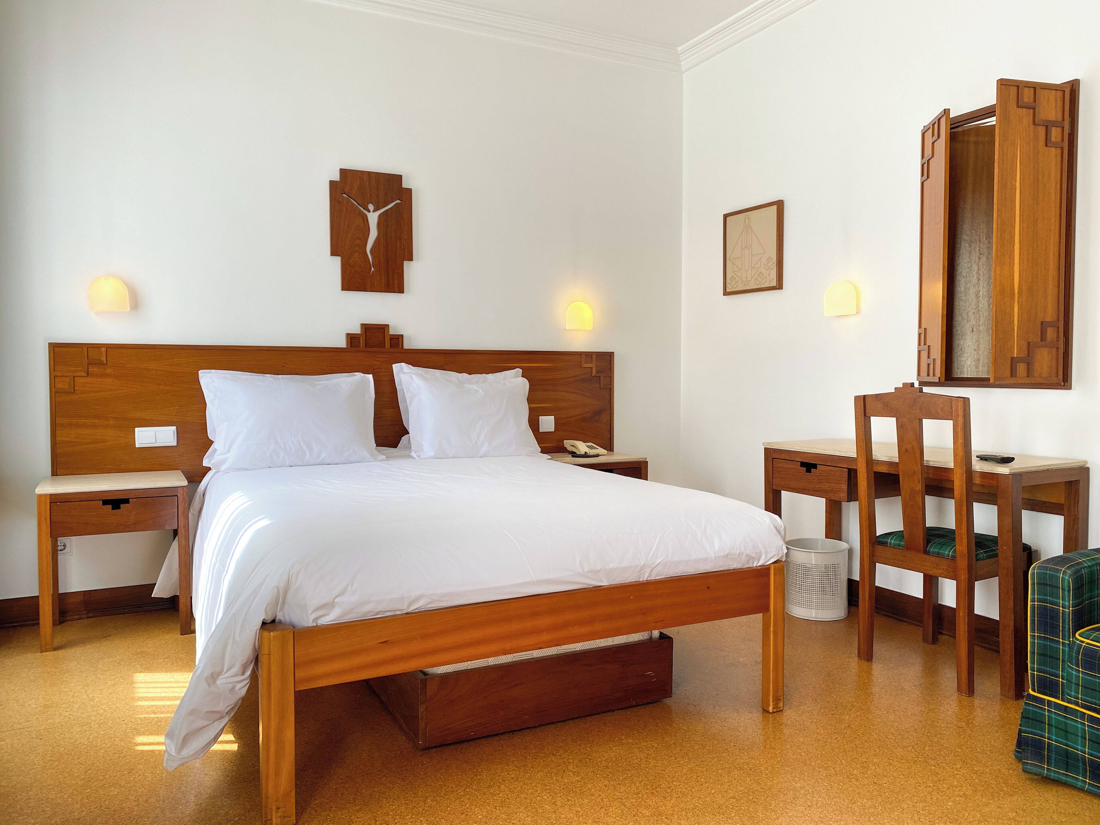 Een hotelkamer met een houten bed, nachtkastjes, een bureau en een stoel.
