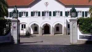 A white building with green shutters, a central entrance with arches, and a red-tiled roof. - Flag Hotel Fátima Irmãs Dominicanas (Ourem)