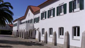 A white building with green shutters and a tiled roof.