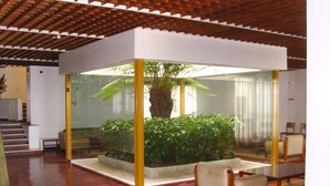 A modern indoor space with a central glass enclosure containing a plant. - Flag Hotel Fátima Irmãs Dominicanas (Ourem)