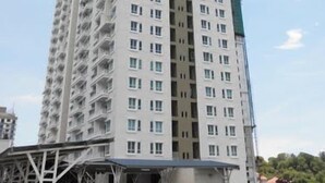 A high-rise residential building with multiple floors, balconies, and a construction crane in the background.