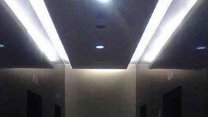 A corridor with a tiled floor, recessed lighting, and doors on both sides.