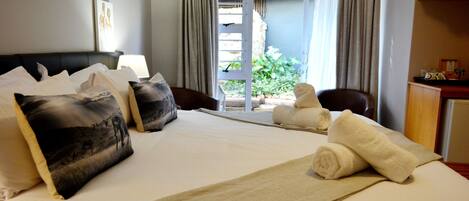 Ein Hotelzimmer mit Bett, Kissen, Decke, einem Sessel und Blick ins Freie.