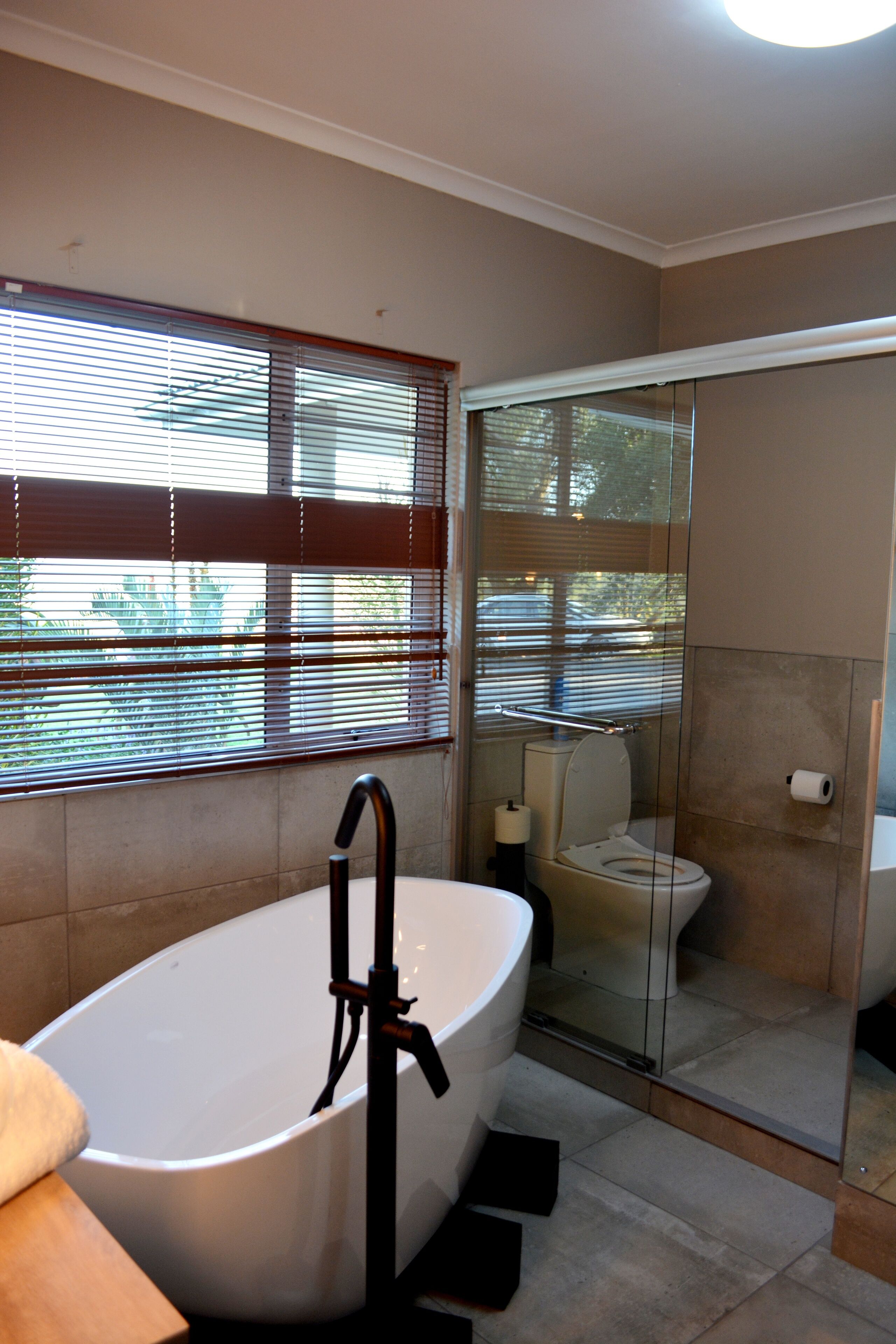 A modern bathroom with a freestanding bathtub, a glass-enclosed shower, and a toilet.