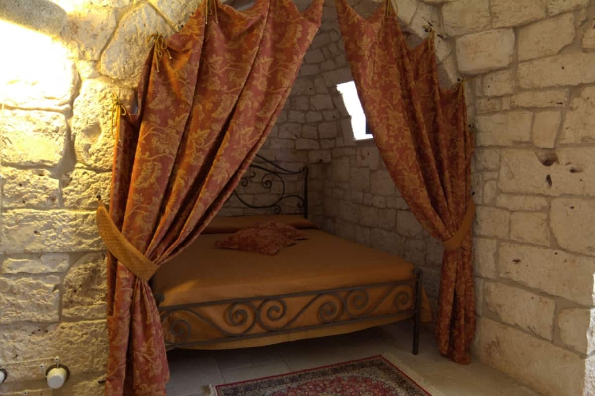 A room with a bed, stone walls, and a window.