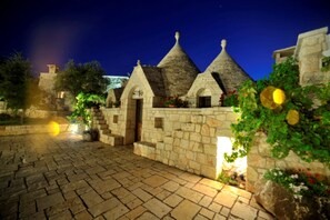 A stone building with conical roofs, a paved courtyard, and surrounding greenery.