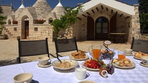 Una mesa para el desayuno al aire libre, con edificios de piedra al fondo.