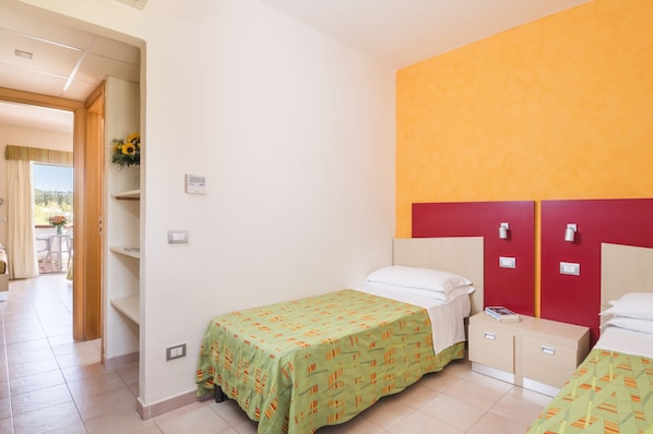 A hotel room with two beds, a red accent wall, and a view of the outdoors. - Sibari Green Resort (Cassano allo Ionio)