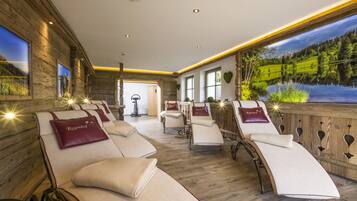 Relax in a serene spa room with reclining chairs, a bathtub, and a tranquil lake view.
