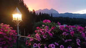 Un jardin aux fleurs éclatantes et un lampadaire, avec des montagnes en arrière-plan.