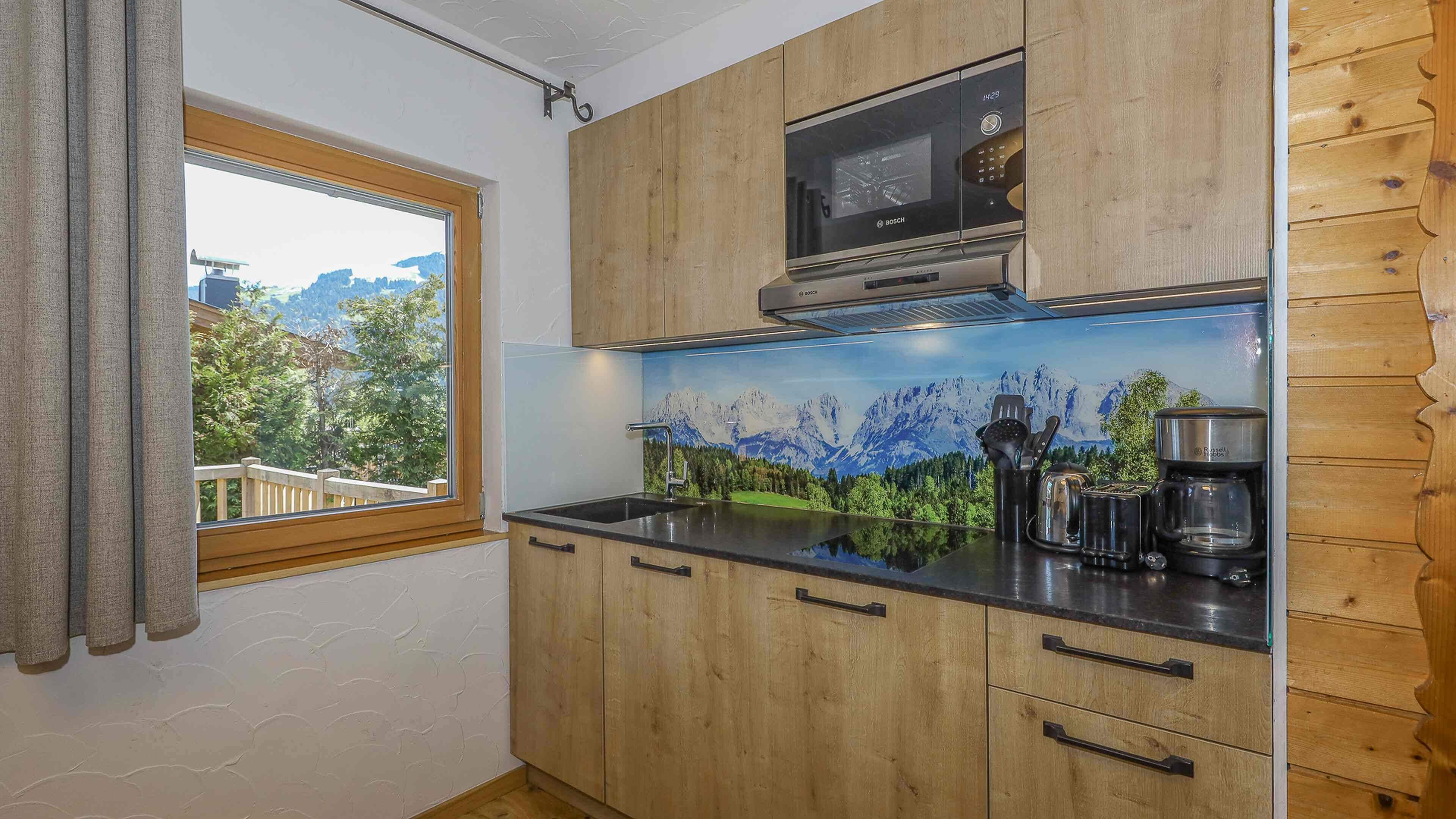 A kitchen with wooden cabinets, a Bosch microwave, and a scenic mountain mural.
