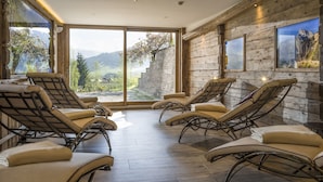Une pièce baignée de lumière, avec des murs en bois, de grandes fenêtres et plusieurs fauteuils inclinables.