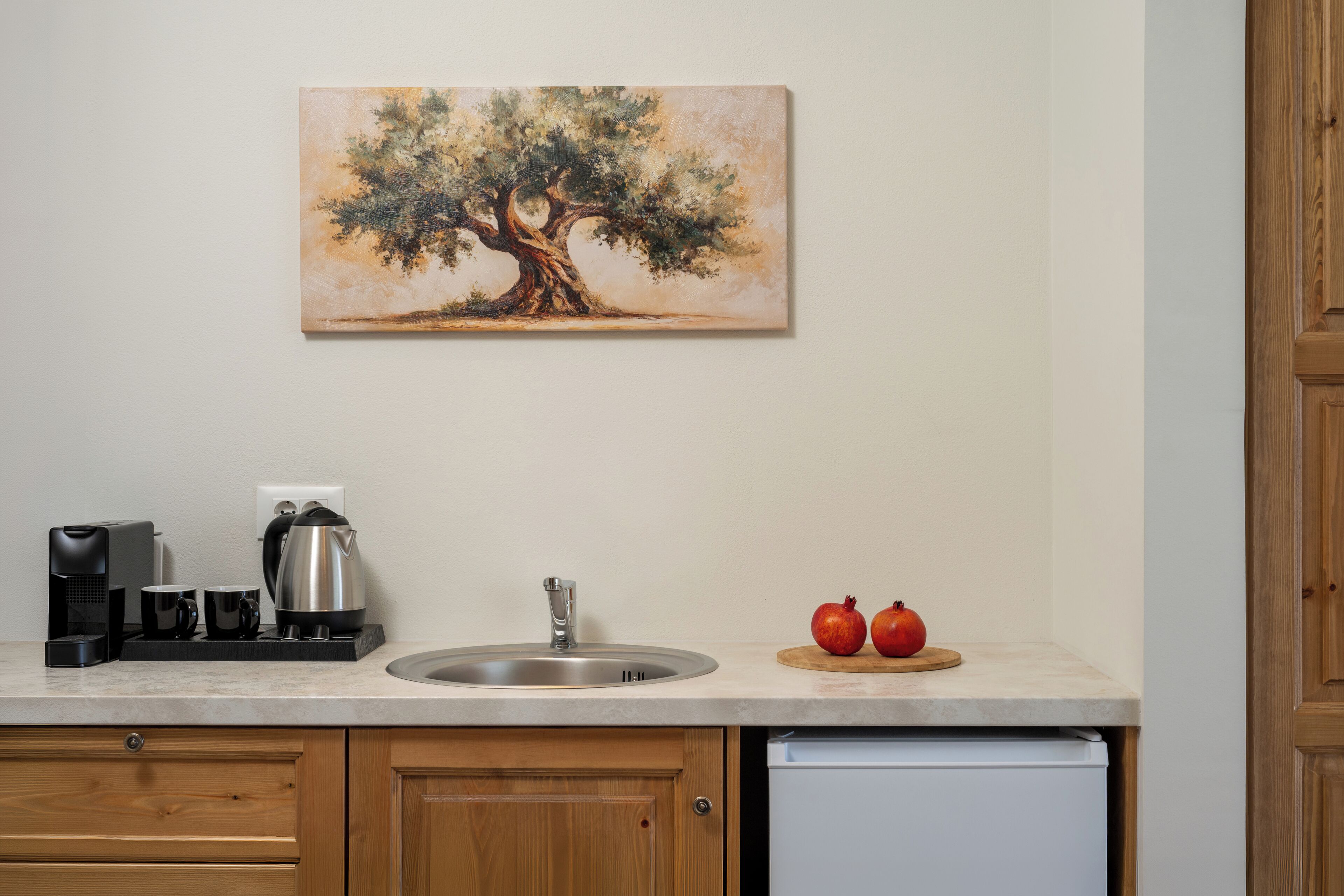 A kitchen with a sink, coffee maker, toaster, and pomegranates on the counter.