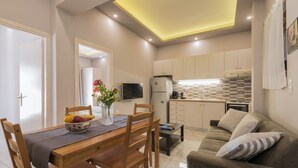 A modern kitchen with a dining area, featuring a wooden table, chairs, a sofa, and a small coffee table. - Katerina (Zakynthos)