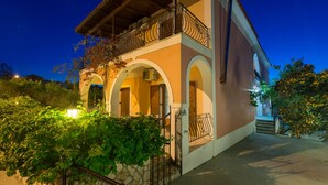 A two-story building with a balcony, arched doorways, and a stone wall. - Katerina (Zakynthos)