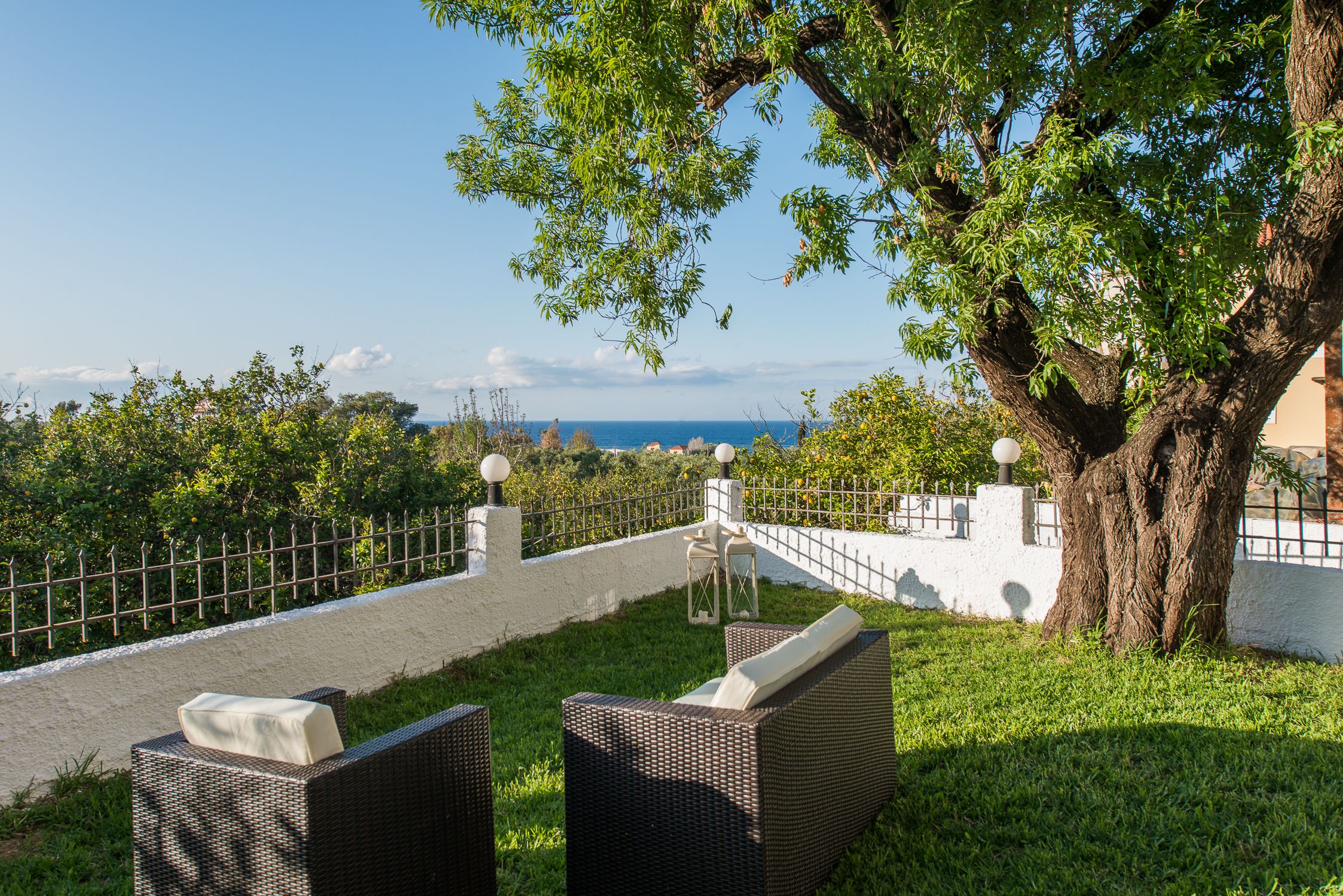 A patio with wicker furniture and a view of the sea.