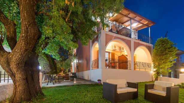 A two-story building with a balcony, outdoor seating area, and a tree. - Katerina (Zakynthos)
