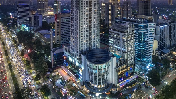 A high-rise building with a modern design, surrounded by other tall buildings and busy streets at dusk. - HARRIS Suites FX Sudirman Jakarta (Jakarta)