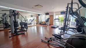 A spacious gym with various exercise equipment, large windows, and a wooden floor. - HARRIS Suites FX Sudirman Jakarta (Jakarta)