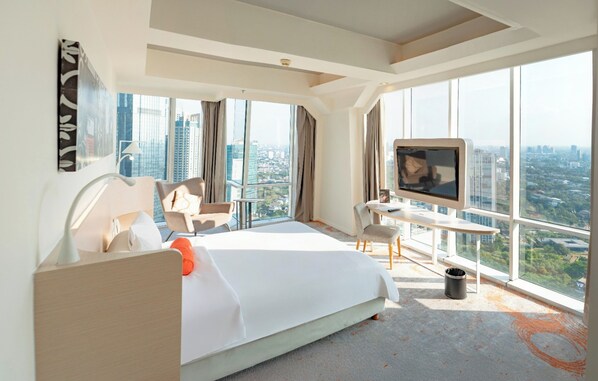 A modern hotel room with a large bed, a desk, a TV, and a city view. - HARRIS Suites FX Sudirman Jakarta (Jakarta)