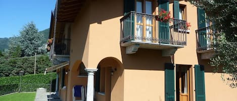 A two-story building with a balcony, stone pathway, and a small garden area.