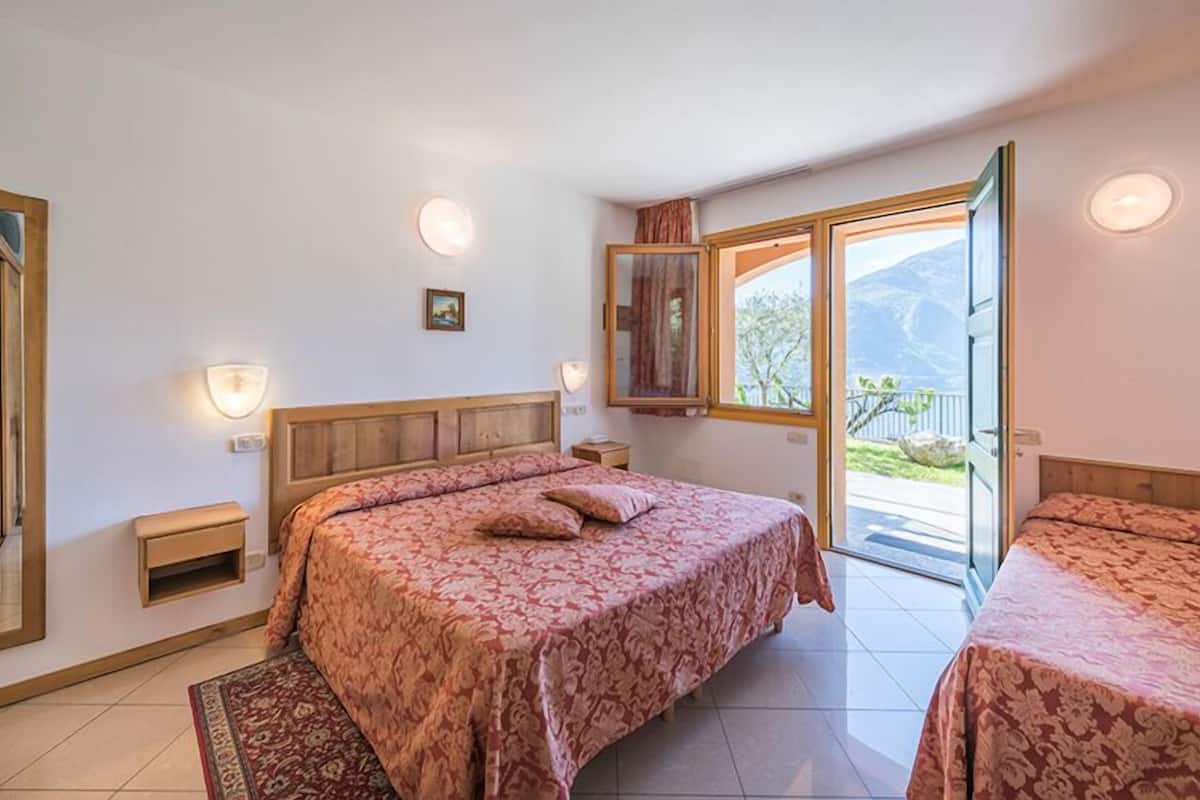 Un dormitorio con una cama grande, una mesita de noche y un ventanal con vistas al exterior.