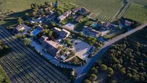 An aerial view of a rural village with houses, vineyards, and a winding road. - Hotel Carcarille - Restaurant le C (Gordes)