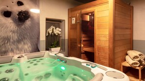 A spa room with a hot tub, wooden sauna, and a wall-mounted heater. - Hotel Carcarille - Restaurant le C (Gordes)