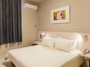 A hotel room with a bed, a nightstand, an air conditioning unit, a painting, and a curtain. - Jinjiang Inn Shanghai Expo Licheng Road (Shanghai)