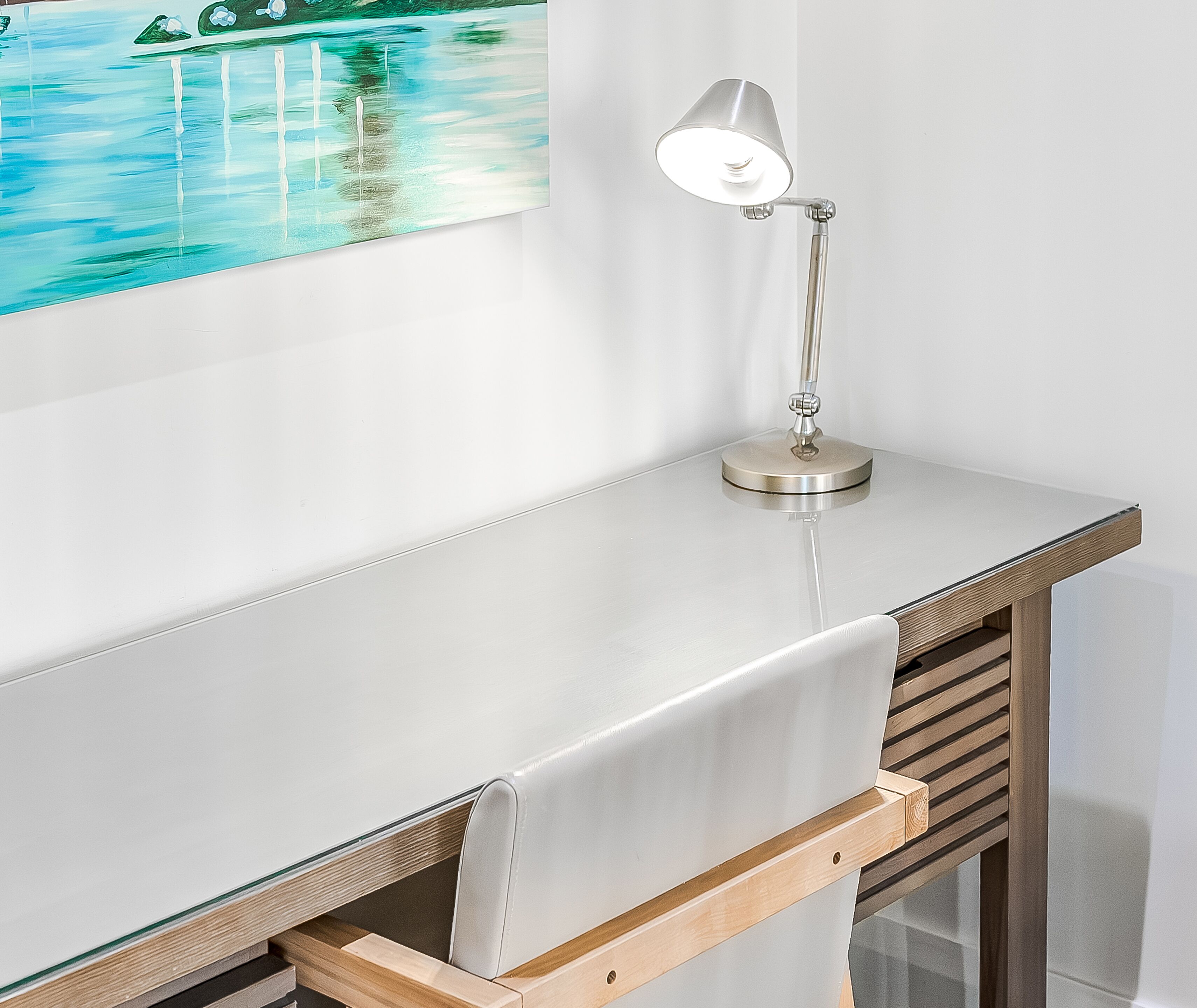 Un bureau avec une lampe, un tableau représentant une scène de plage et un motif de lattes de bois sur le côté.