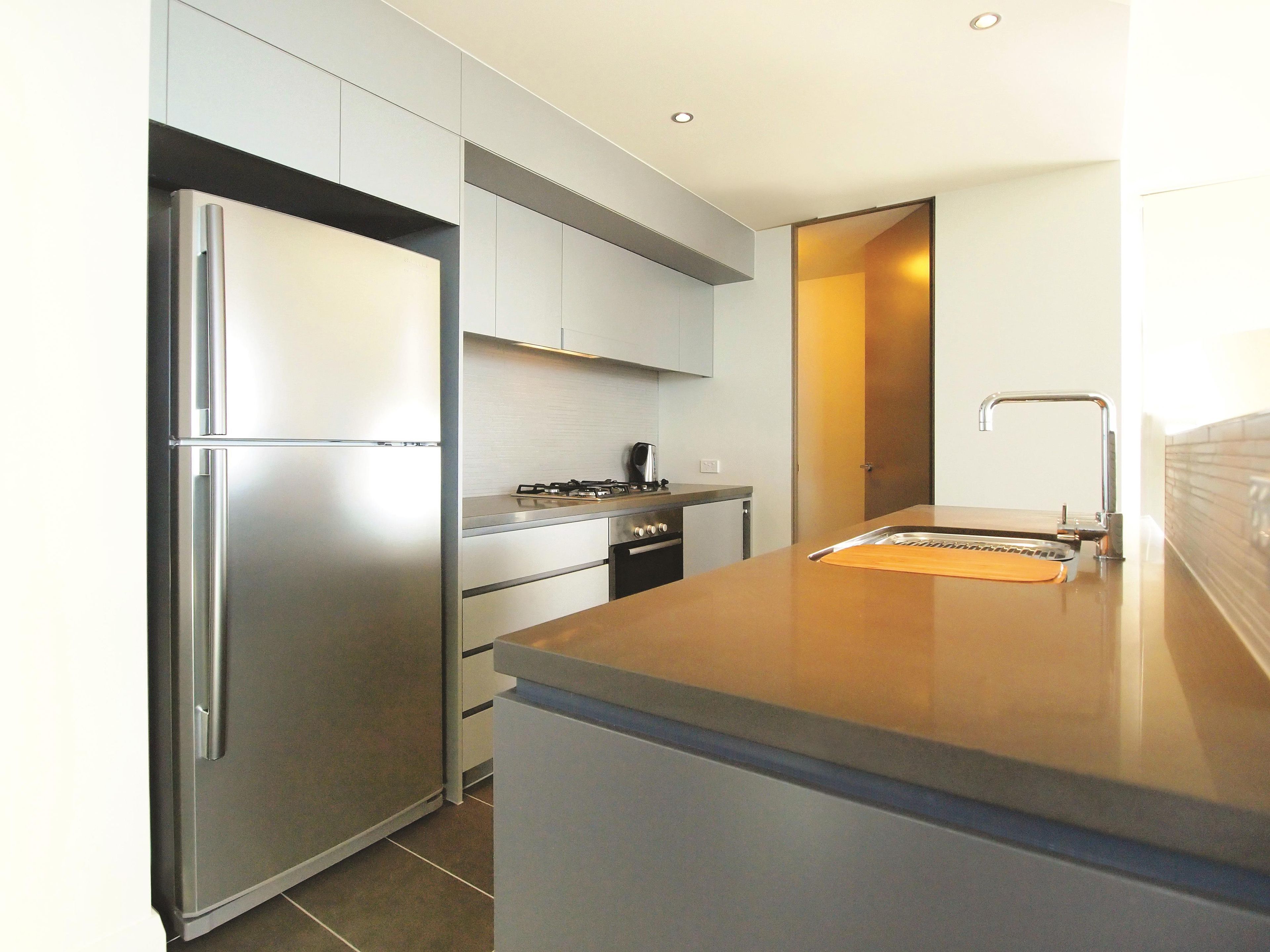 A modern kitchen with a stainless steel refrigerator, a gas stove, and a sink.