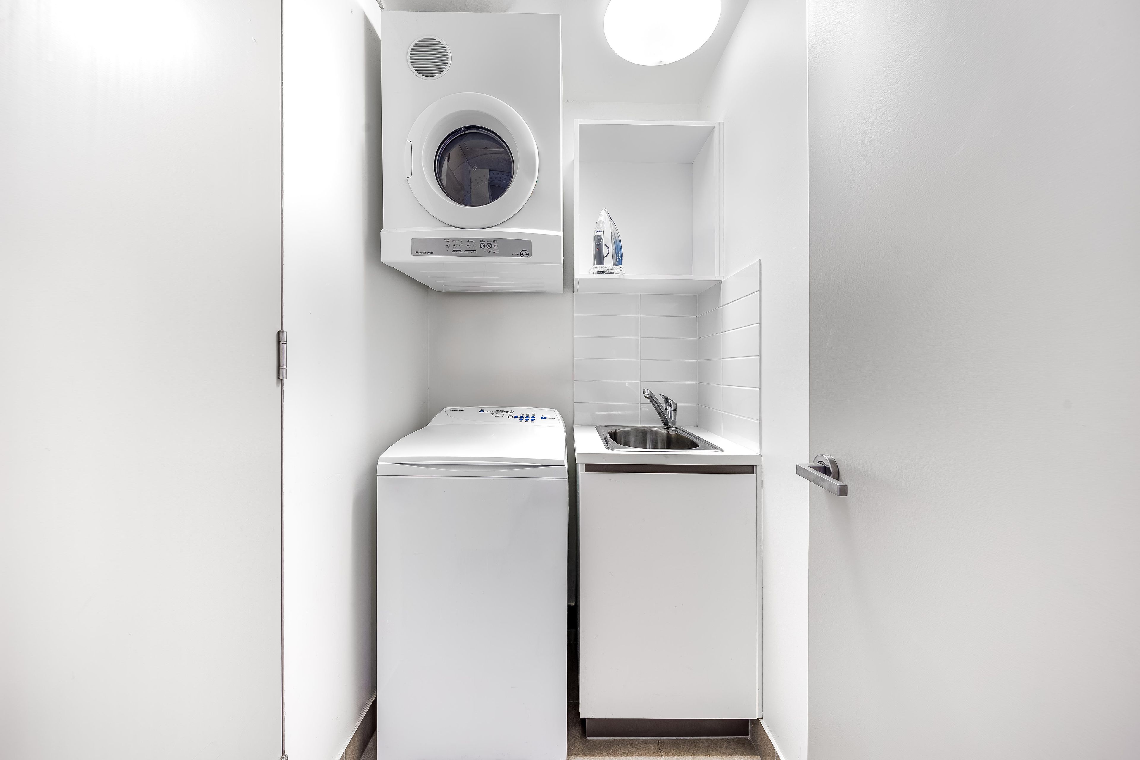 Een kleine wasruimte met een wasmachine, een droger en een wasbak.