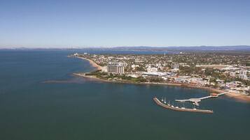 An aerial view of a coastal city with a marina, buildings, and a beach.