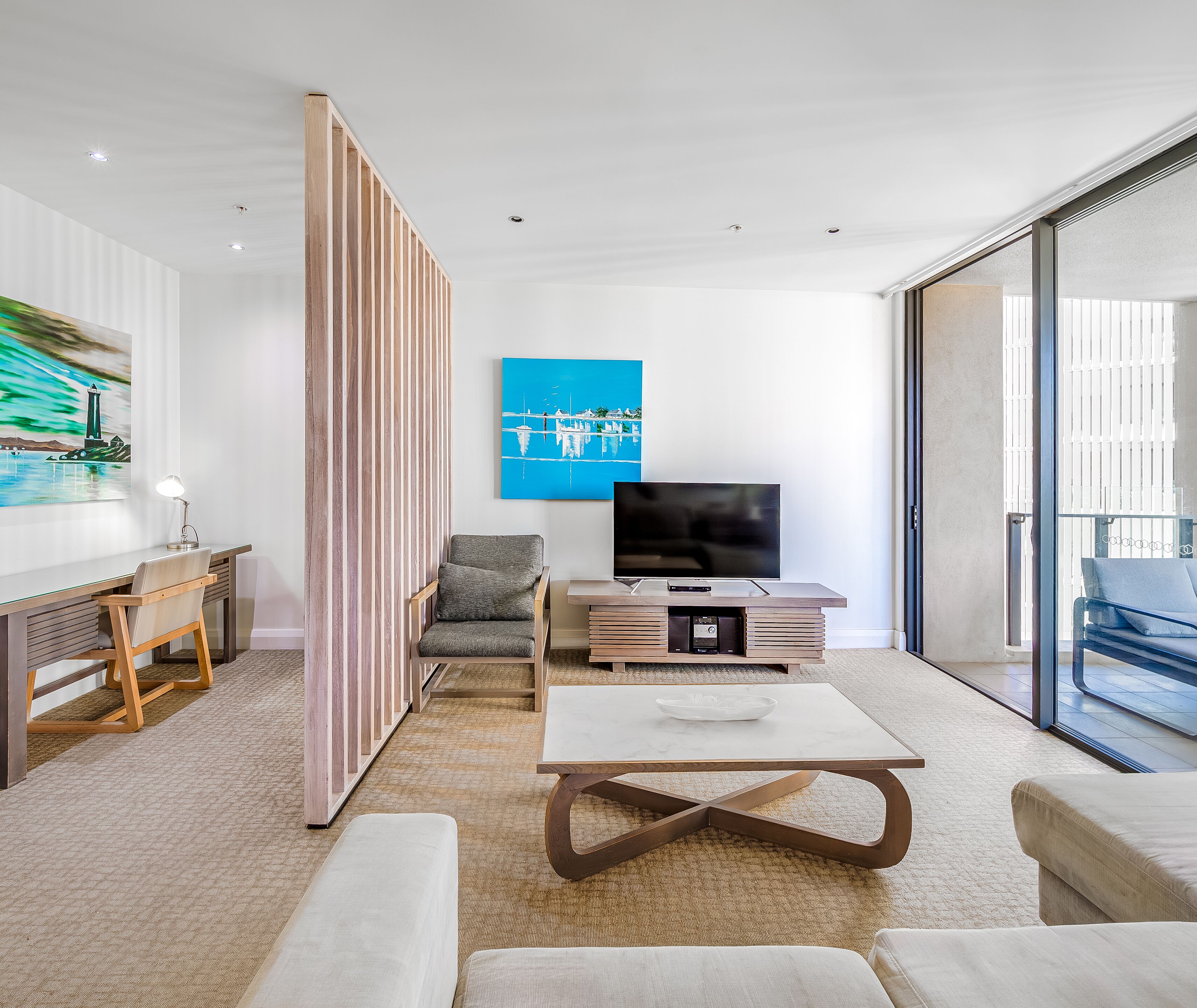 Een moderne woonkamer met een televisie, zitmeubels en kunstwerken.
