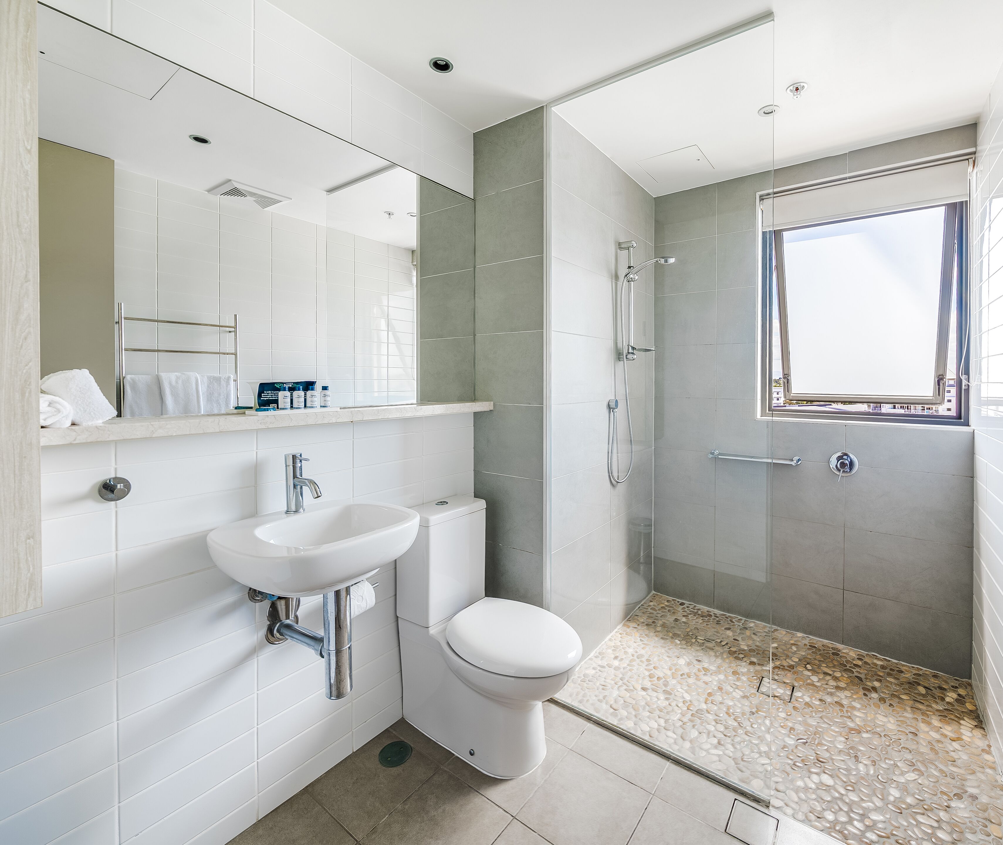 Ein modernes Badezimmer mit Waschbecken, Toilette und Dusche, alles in Weiß.